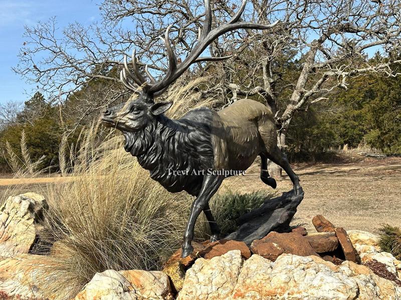 Bronze Elk — leaping across a natural rock outcrop at the ranch entrance
