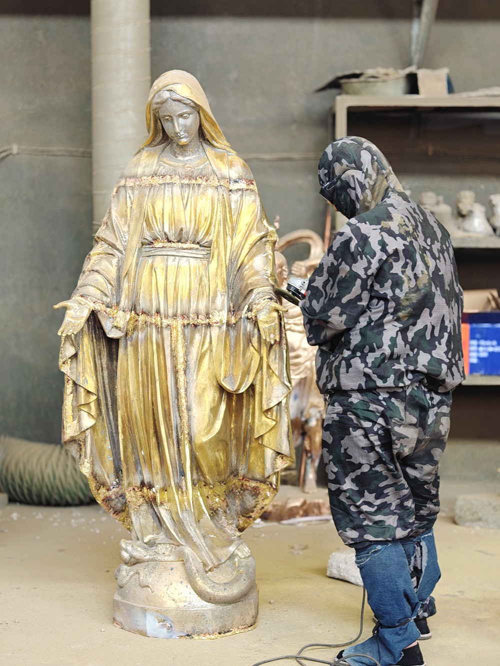 artisan polishing golden bronze Virgin Mary statue