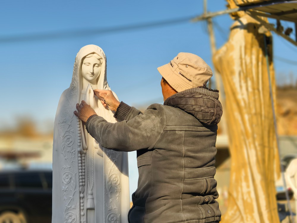 artisan polishing marble Virgin Mary statue