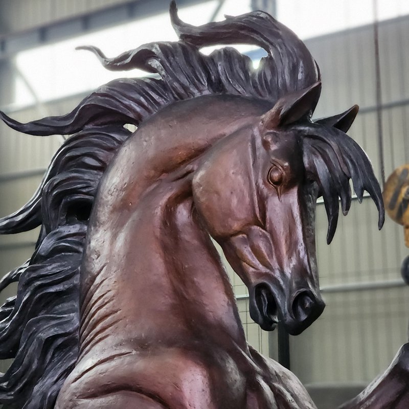Close-up of a rearing bronze horse face and flowing mane