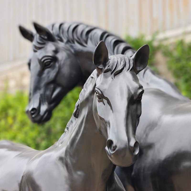 Front view of two finished life-size bronze horse sculptures