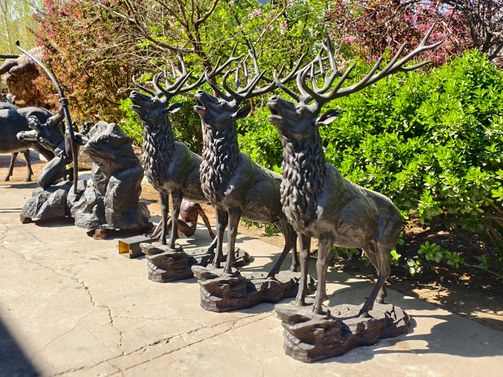 Multiple finished bugling bronze elk statues displayed at the workshop