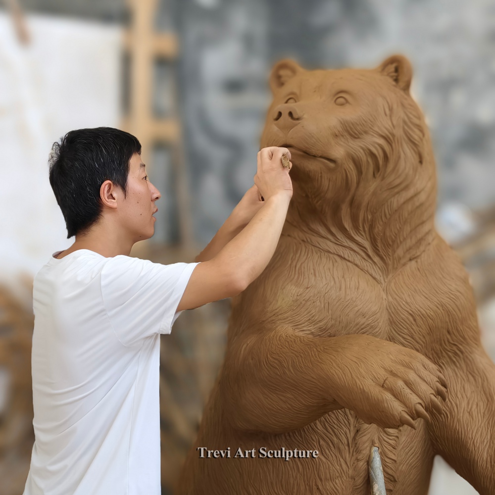 Sculptor carving the face of a standing bear clay model