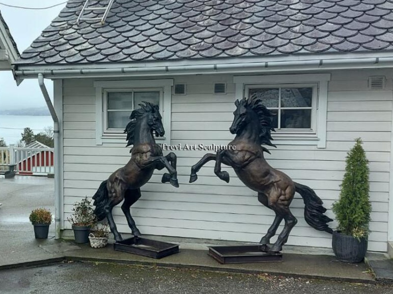 Pair of rearing bronze horse statues at an outdoor entrance